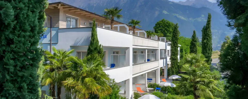 Glanzhof Hotel & Apartments in Marling – Hotelgebäude mit Palmen und Bergblick | Wellnesshotel Südtirol