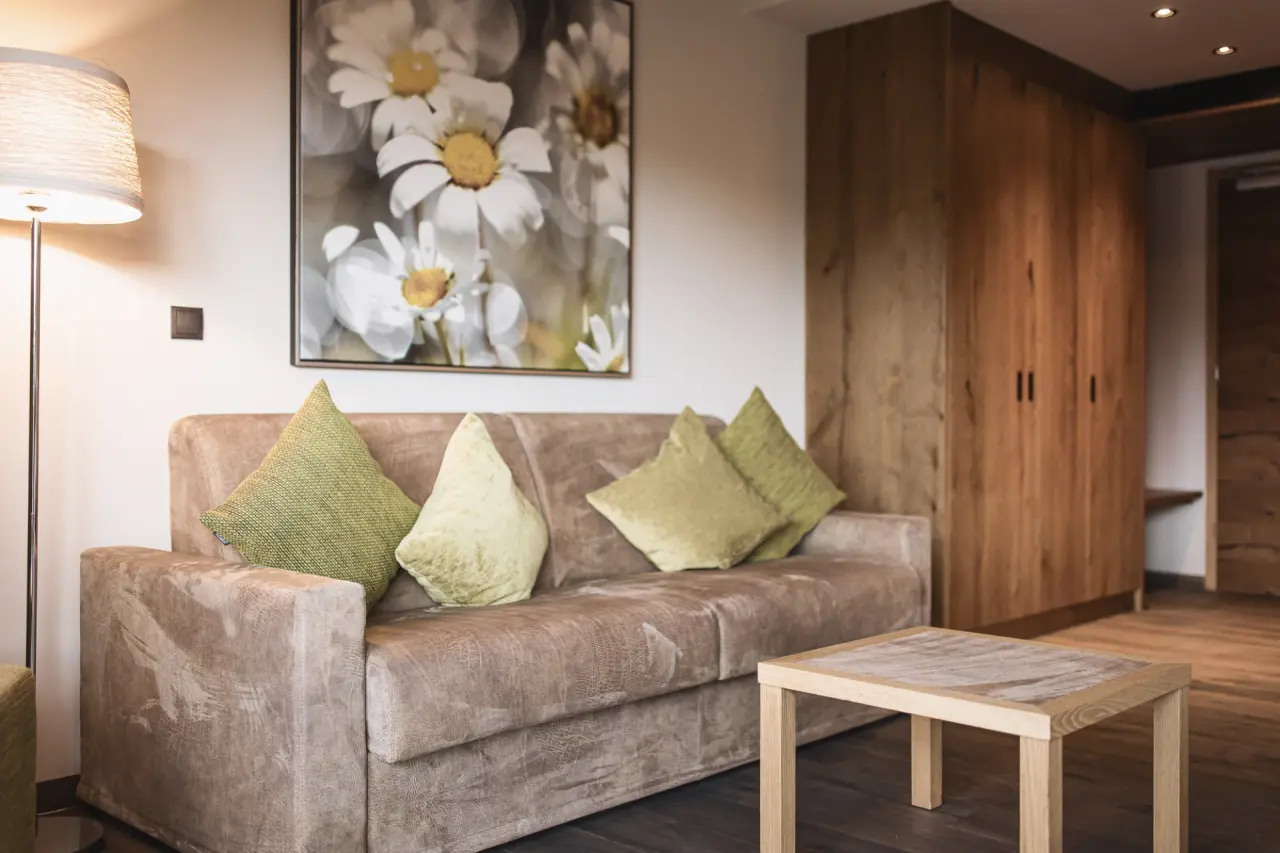 Terentnerhof in Terenten – Gemütlicher Wohnbereich mit Sofa und Kunstwerk im Hotelzimmer | Wellnesshotel Südtirol