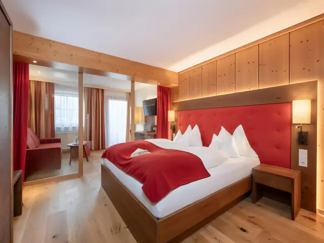 Hotel Alpenland in Obertauern – Komfortables Doppelzimmer mit Holzelementen und rotem Kopfteil | Wellnesshotel Salzburger Land