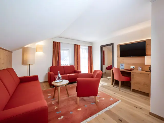 Hotel Alpenland in Obertauern – Gemütlicher Wohnbereich einer Suite mit roten Sofas | Wellnesshotel Salzburger Land