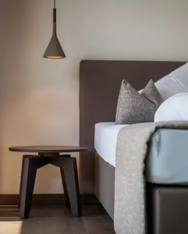 Klein Fein Hotel Anderlahn in Plaus – Nachttisch mit Lampe und Teil eines Hotelbettes | Wellnesshotel Südtirol
