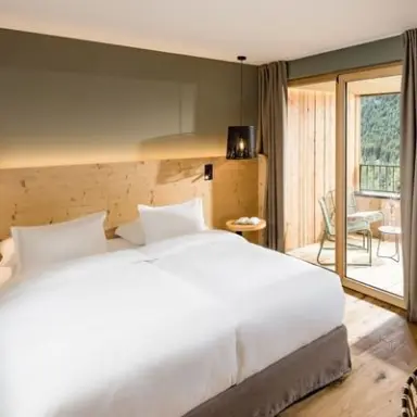 Falkensteiner Hotel Antholz in St. Martin in Gsies – Helles Doppelzimmer mit Balkon und Bergblick | Wellnesshotel Südtirol