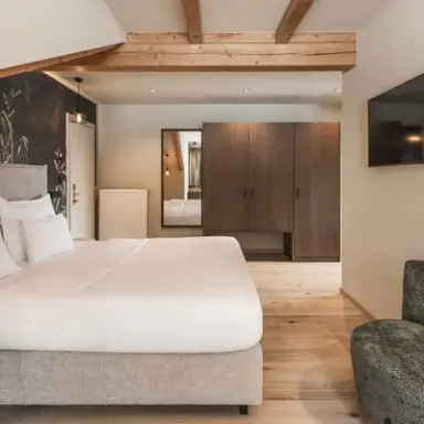 Falkensteiner Hotel Antholz in St. Martin in Gsies – Helles Hotelzimmer mit Doppelbett und Holzmöbeln | Wellnesshotel Südtirol